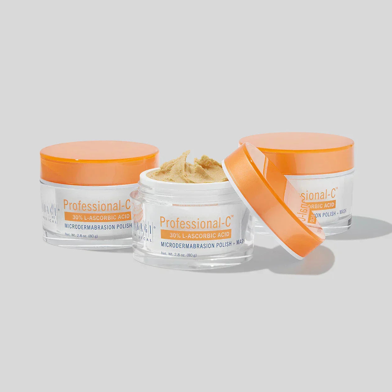 Three skincare jars with orange lids on a light gray background